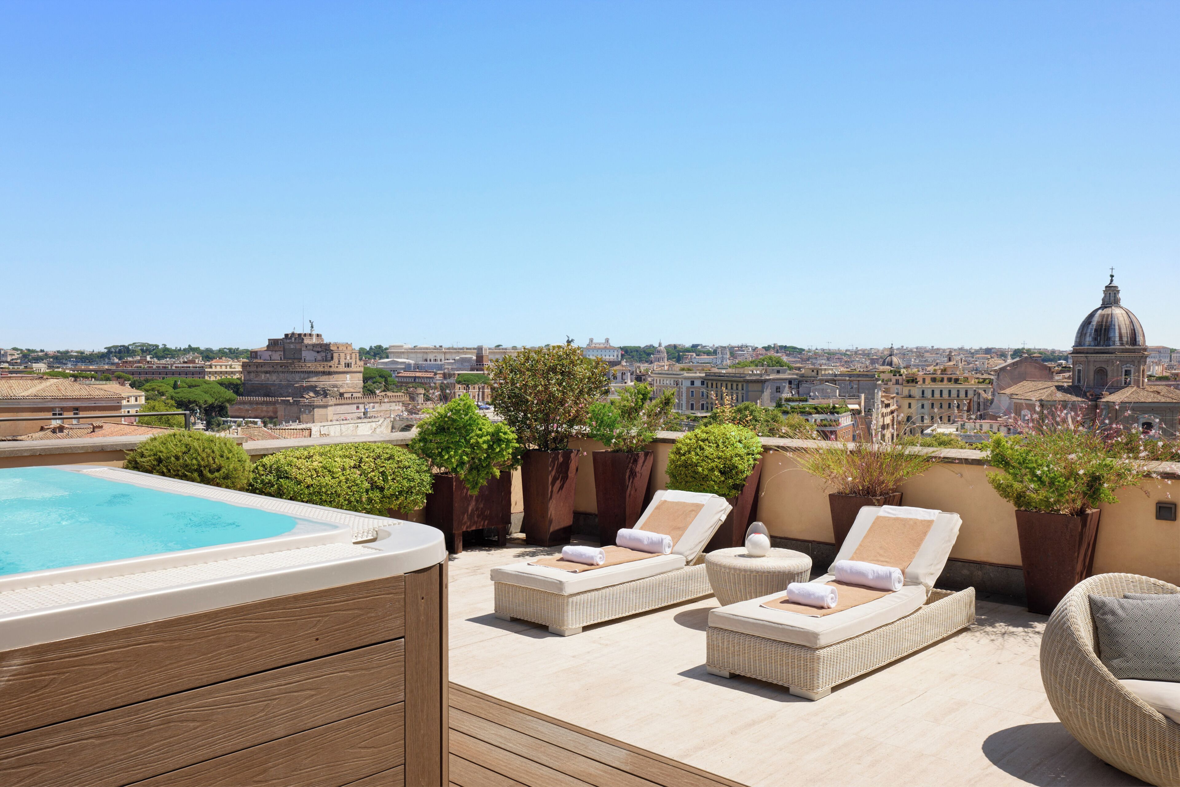 A rooftop terrace with a swimming pool, lounge chairs, and potted plants.
