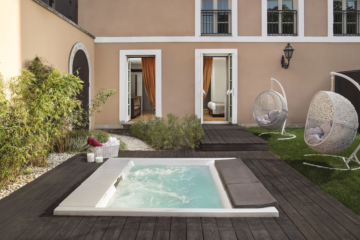 Un'area benessere con vasca idromassaggio, due poltrone a dondolo e un pontile in legno.
