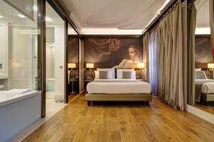 Una camera d'albergo con un letto grande, comodini con lampade, un pavimento in legno e un affresco sulla parete.
