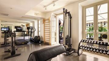 A gym with exercise equipment, a treadmill, and a dumbbell rack.