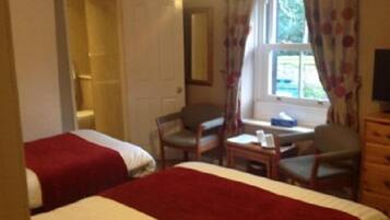 A room with two beds, a desk, a chair, and a dresser.