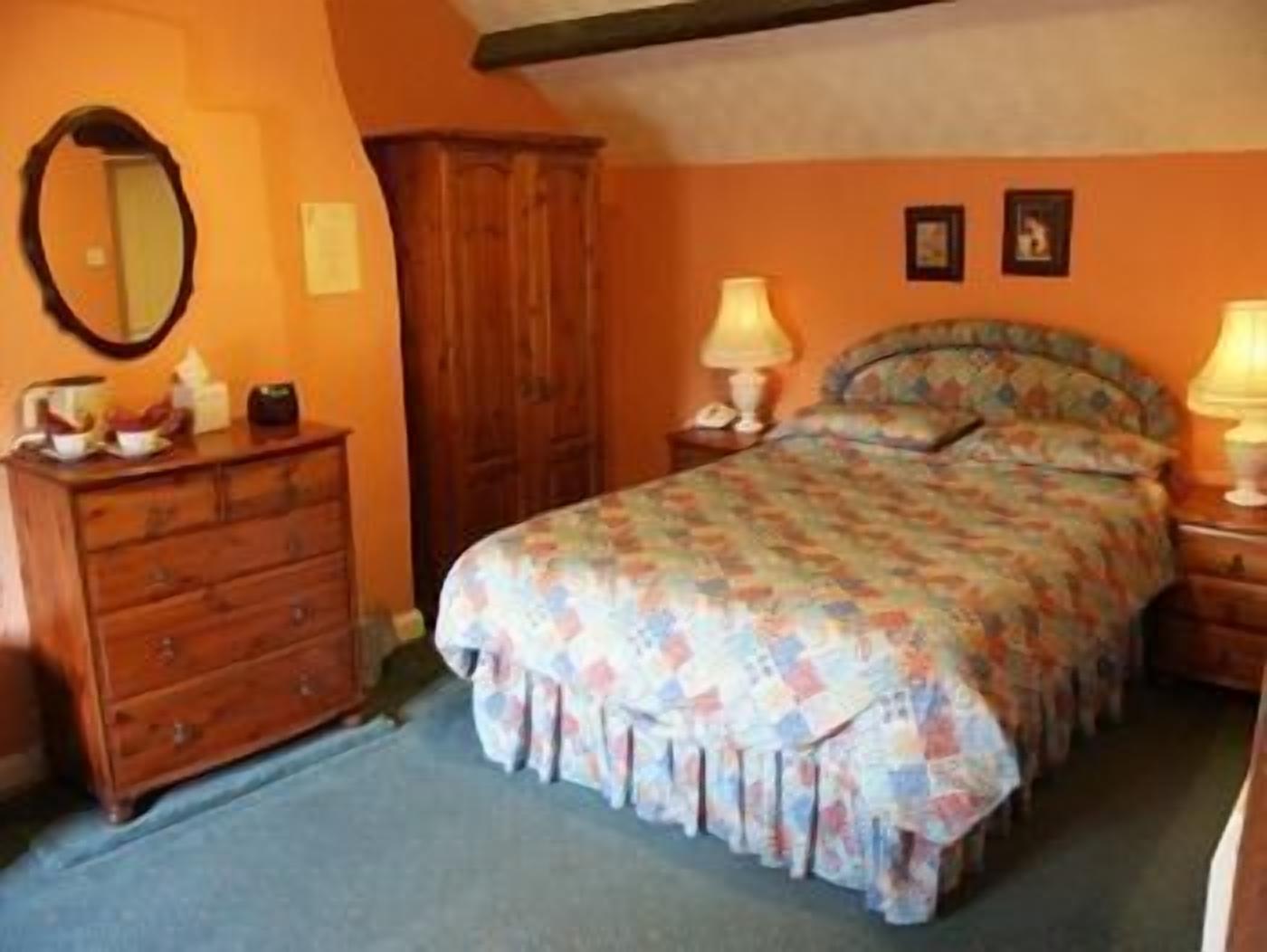 A bedroom with a bed, dresser, and two bedside lamps.