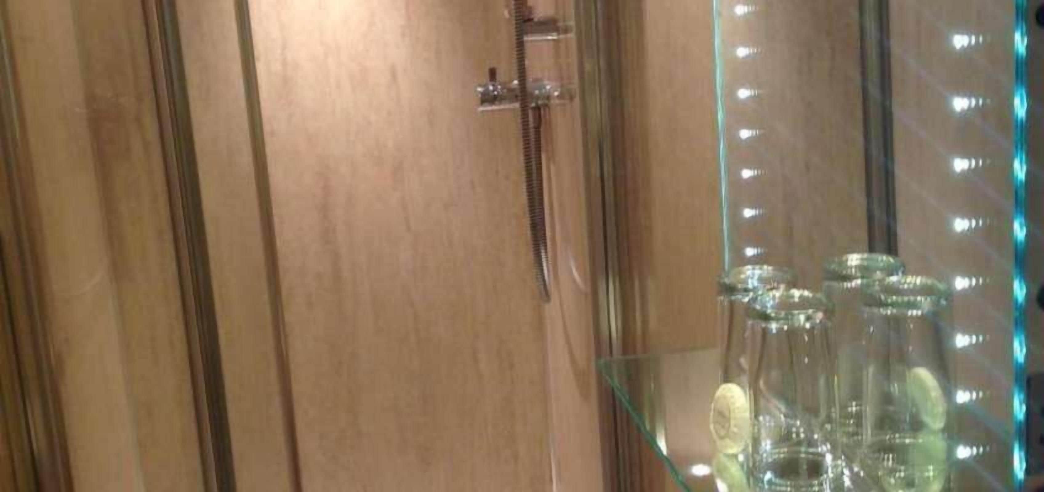 A wooden door with a towel rack and a glass cabinet with bottles.