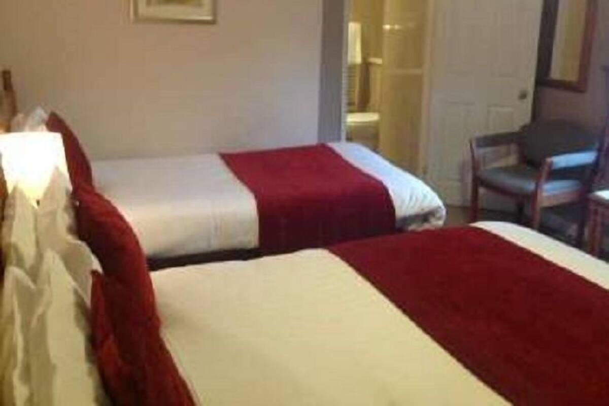 Ett hotellrum med två sängar, en stol och en dörr som leder till ett badrum.