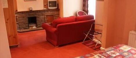 Una habitación acogedora con un sofá rojo, una chimenea y una colcha estampada.