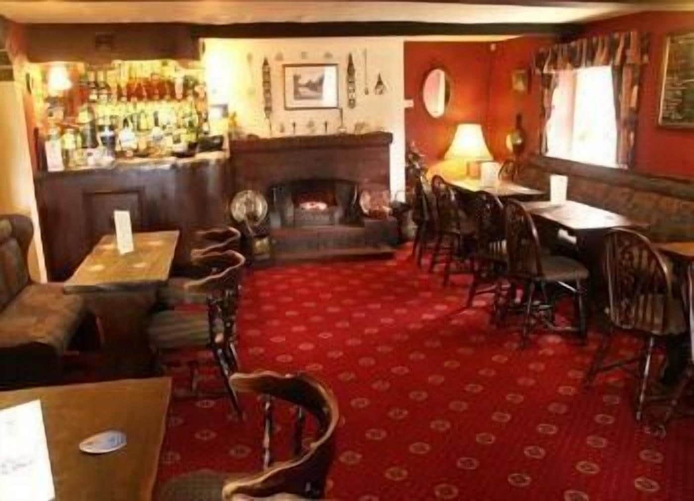 Un pub tradicional con zona de bar, mobiliario de madera y alfombra estampada.