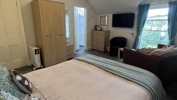 Un dormitorio con una cama grande, un armario, un televisor y una ventana con cortinas.