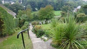 A set of concrete steps leading up to a house, surrounded by lush greenery and a well-maintained garden. - Bryn Derwen Guest House (Conwy)