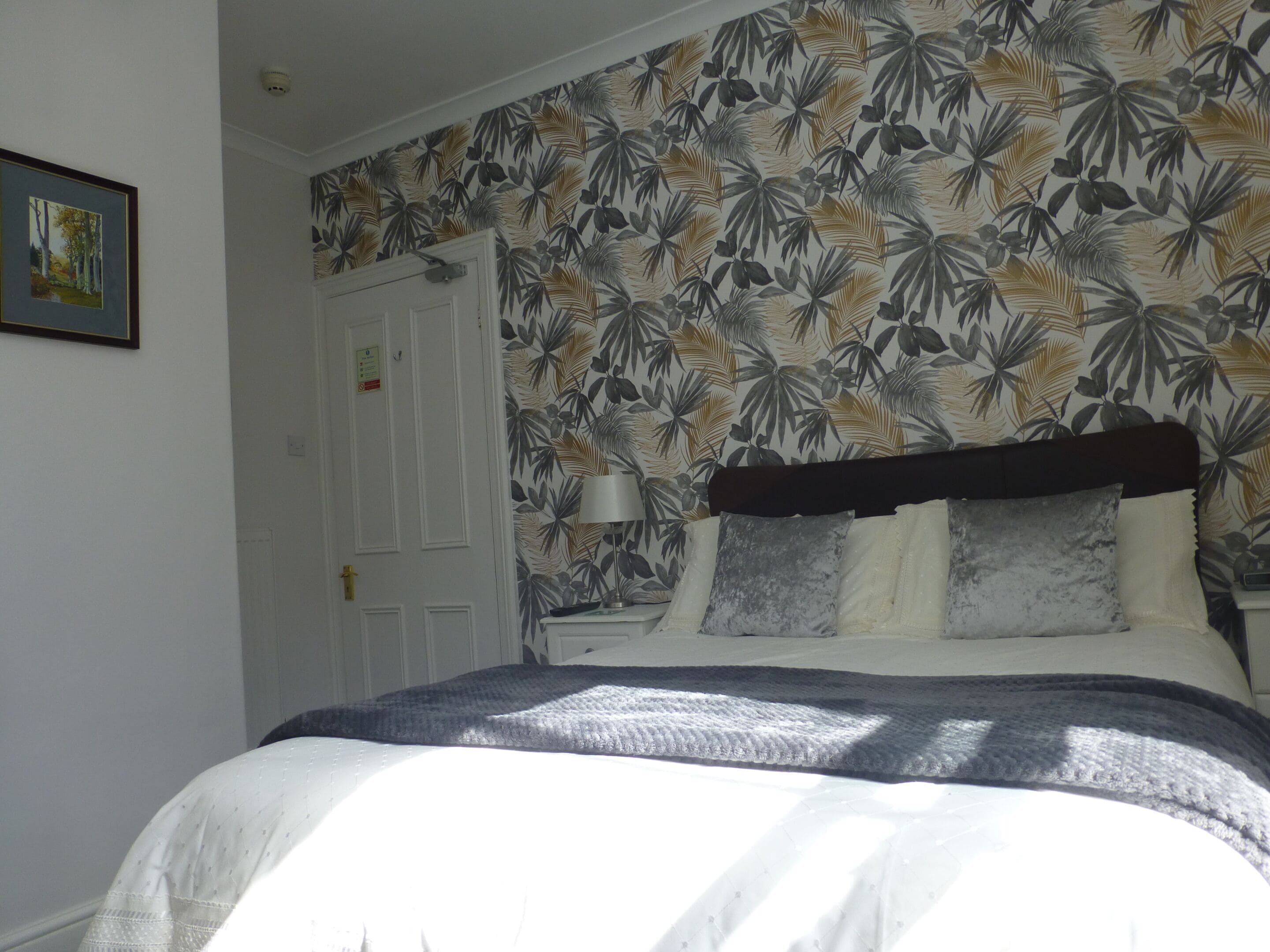 A bedroom with a bed, a nightstand, a lamp, and a door.