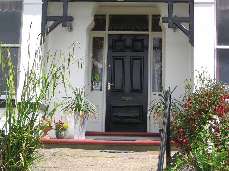 A building with a black door, white walls, and a red threshold.