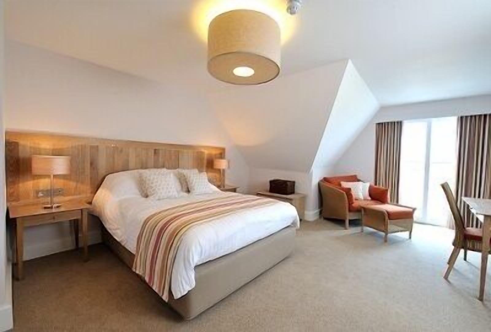 A modern hotel room with a large bed, bedside tables, a desk, and a chair.