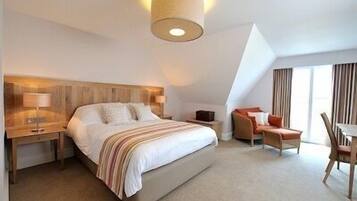 Una habitación de hotel moderna con una cama grande, mesitas de noche, un escritorio y una silla.