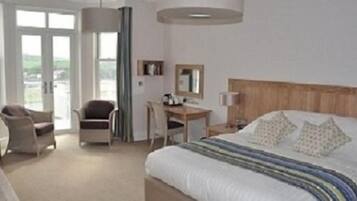 A hotel room with a large bed, a desk, a chair, and a view through the window.