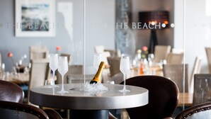 A dining table with a bottle of champagne and two glasses on ice, surrounded by chairs.