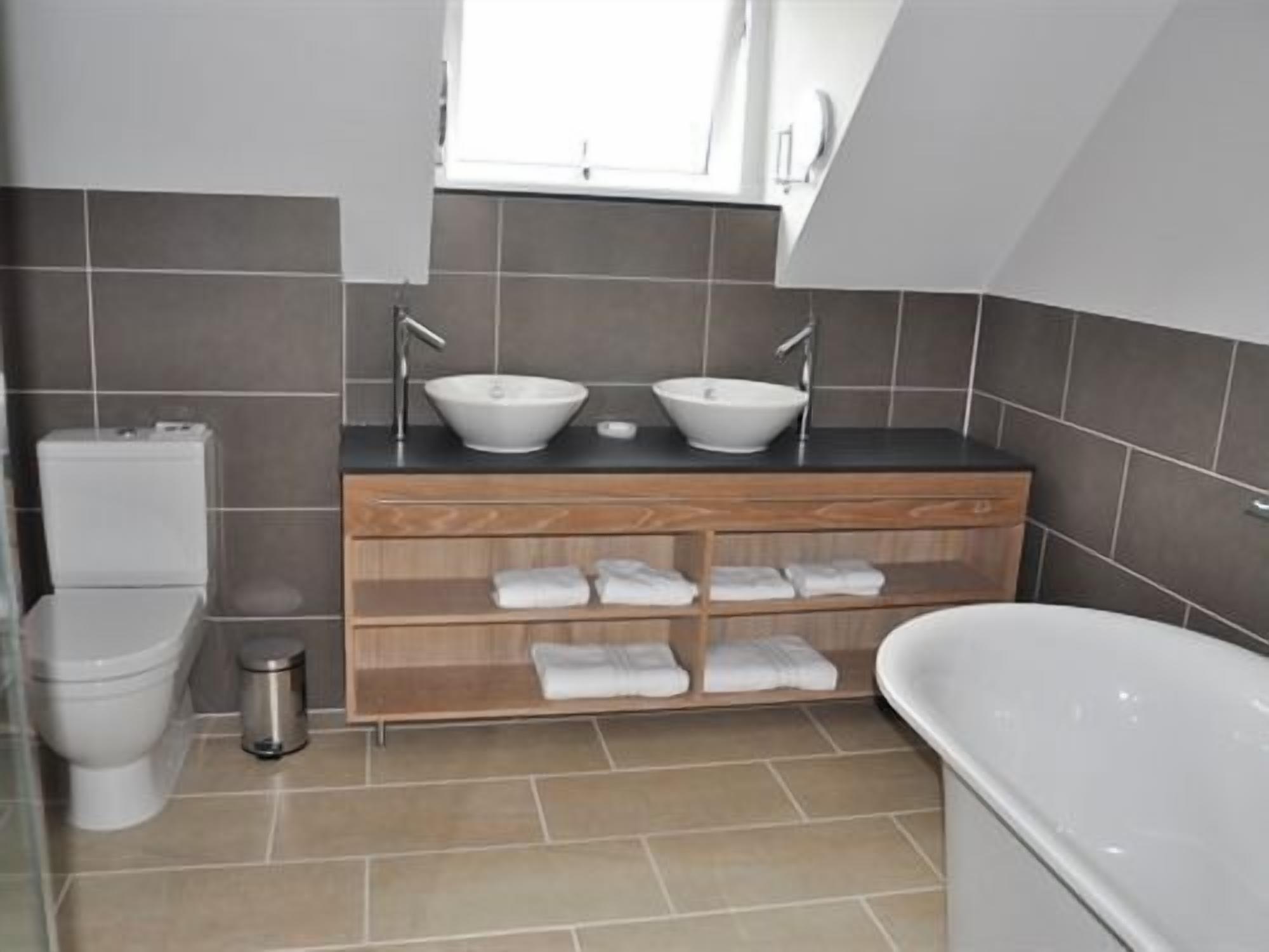 A modern bathroom with two sinks, a toilet, a shower, and a bathtub.