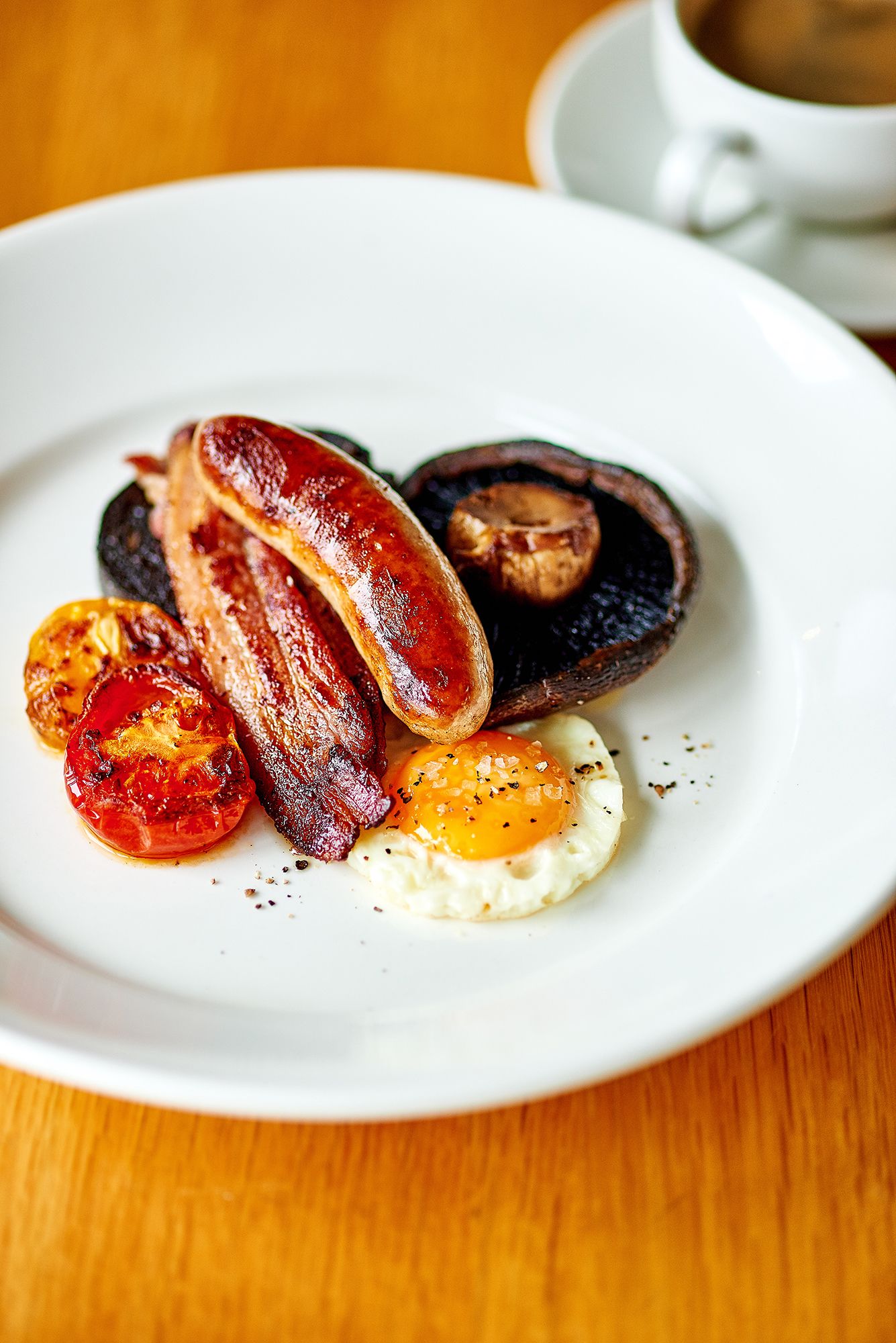 A plate of breakfast food including bacon, eggs, and tomatoes.
