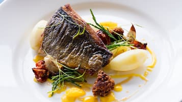 Un plato con pescado, patatas y guarniciones.