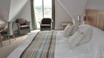Un dormitorio con cama, dos sillas, una mesita de noche y una lámpara.