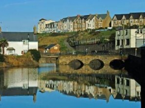 A waterfront property with a bridge, reflecting buildings, and a calm water body. - The Beach at Bude (Bude)