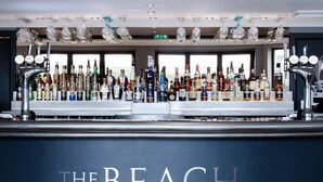 A bar with a variety of liquor bottles and a sign that reads "THE BEACH".