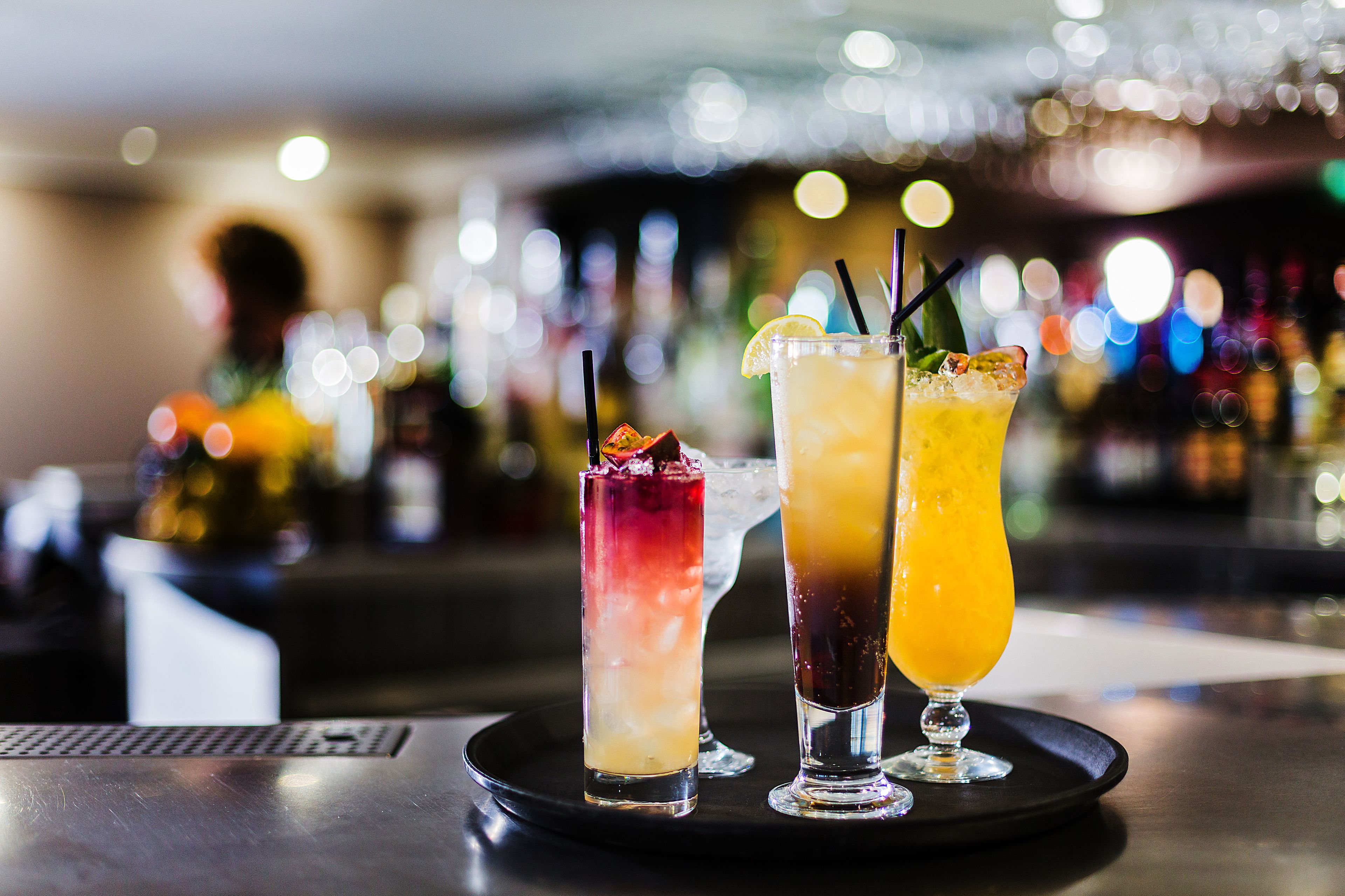 Drie cocktails op een bargedeelte met een onscherpe achtergrond van lichtjes.
