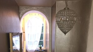 A staircase with a red carpet leading to a landing, a chandelier, and a mirror on the wall. - Castle Lodge Hotel (Ross-on-Wye)