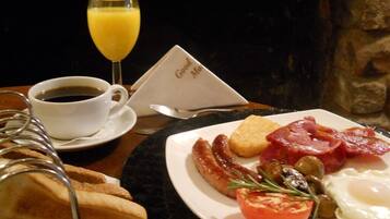 A breakfast plate with eggs, bacon, sausage, toast, and a glass of orange juice.
