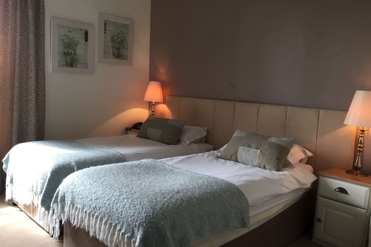 A double bed with a headboard, two bedside tables, a nightstand, and a lamp.