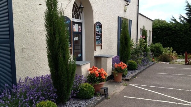 A building with a white facade, a black awning, and a parking lot. - Castle Lodge Hotel (Ross-on-Wye)