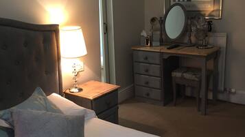 A neatly arranged bedroom with a bed, bedside lamp, dresser, and a mirror.