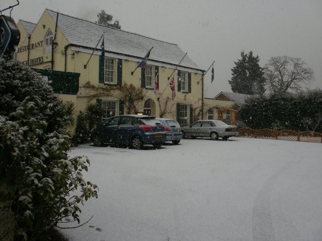 Een gebouw met een bord waarop staat restaurant en hotel. Parkeermogelijkheden zijn aanwezig en er ligt sneeuw op de grond.