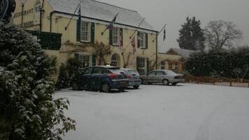 Een gebouw met een bord waarop staat restaurant en hotel. Parkeermogelijkheden zijn aanwezig en er ligt sneeuw op de grond.