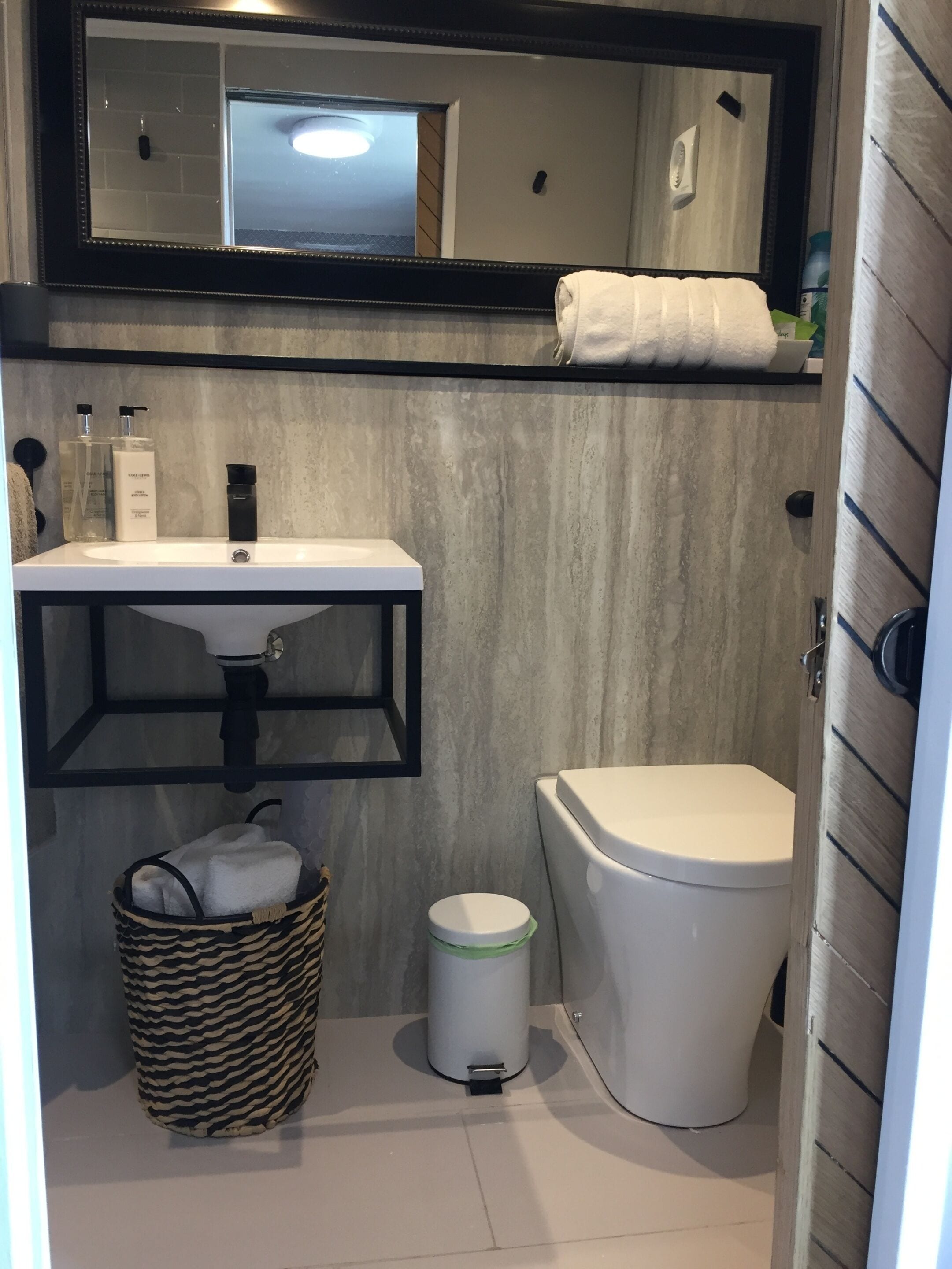 Un baño pequeño con un lavabo blanco, un inodoro y un espejo sobre el lavabo.