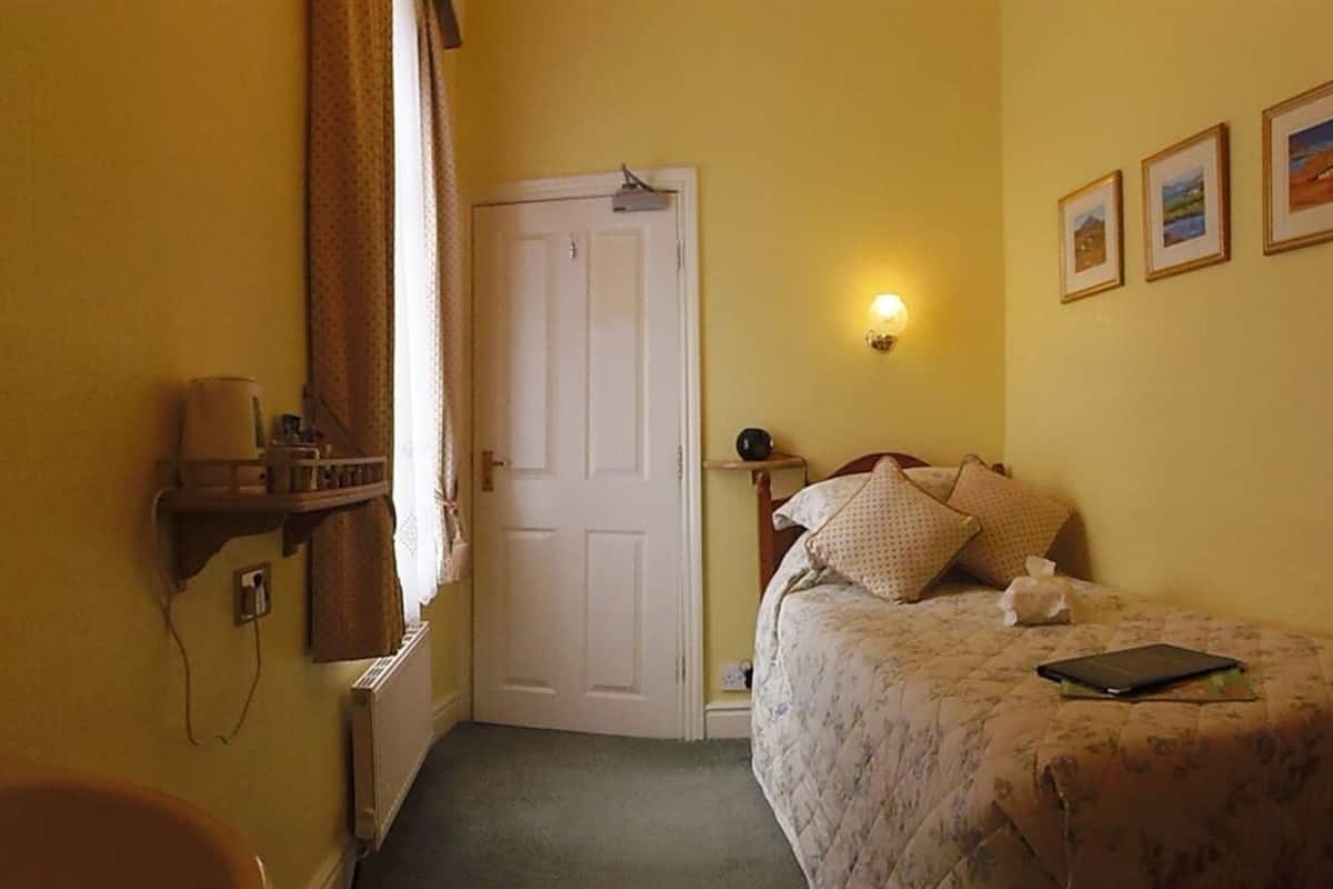 Ein Schlafzimmer mit einem Bett, einem Nachttisch, einer Lampe, einem Heizkörper und einer Tür.
