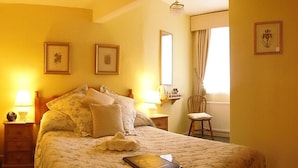 A hotel room with a bed, bedside tables, a chair, and framed pictures on the walls. - City Guest House (York)
