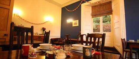 A dining room with a wooden table set for four, surrounded by chairs.