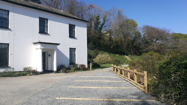 A white building with a gravel driveway and a wooden bridge. - Laston House (Ilfracombe)