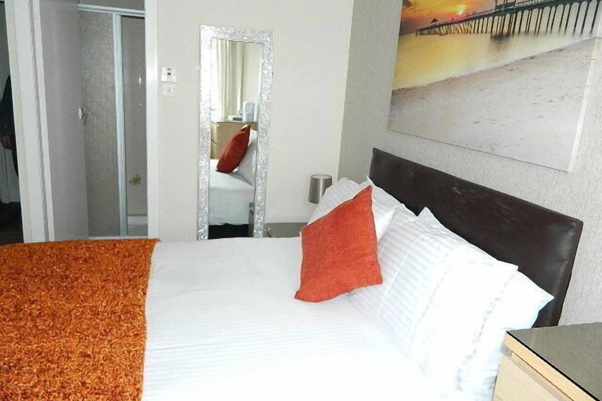 A hotel room with a bed, a mirror, a painting, and a door.