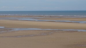 A wide sandy beach with gentle waves and a clear sky. - Ocean Bay Hotel (Blackpool)