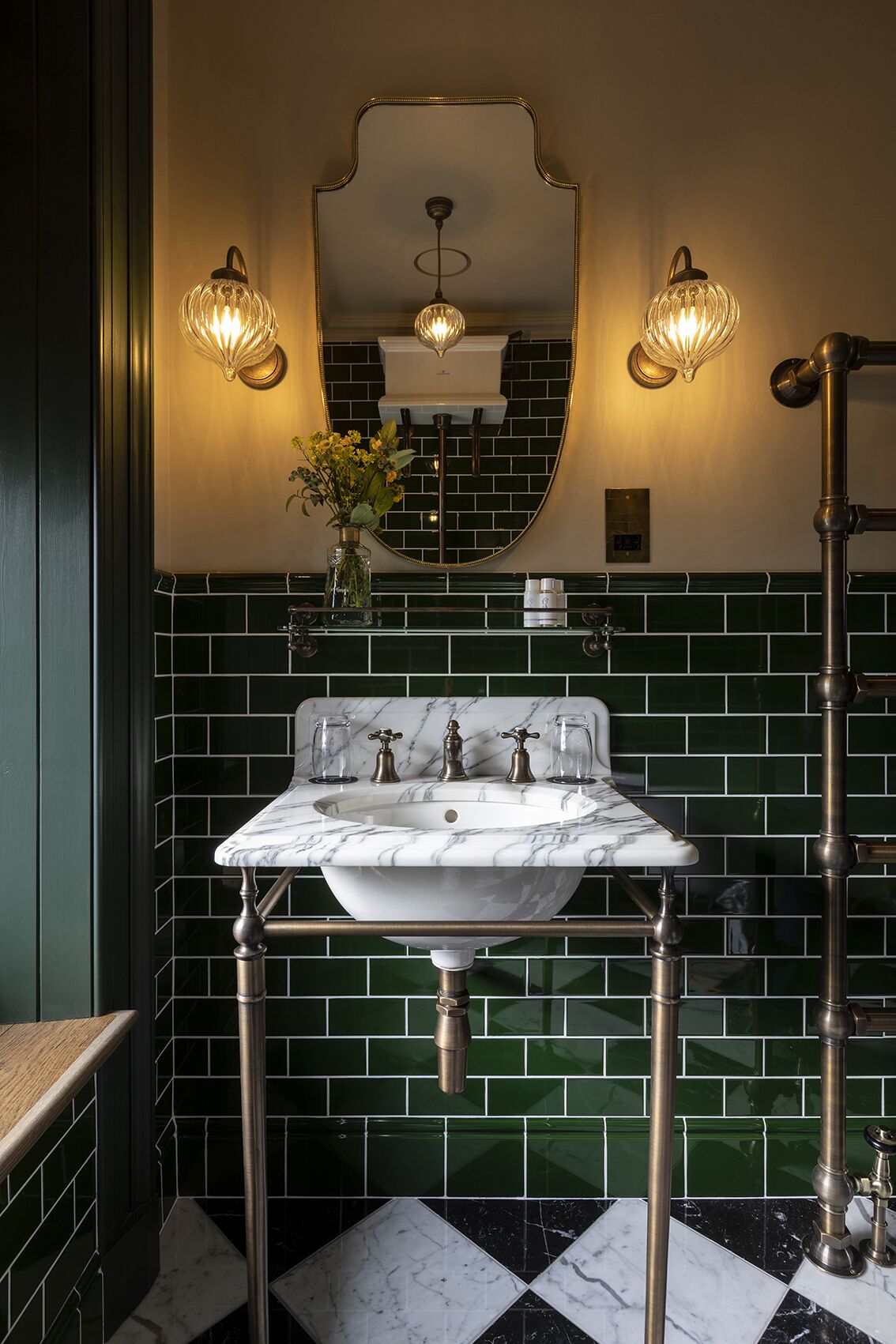 Une salle de bain avec un lavabo en marbre blanc, des carreaux de céramique verts et un miroir avec un cadre doré.