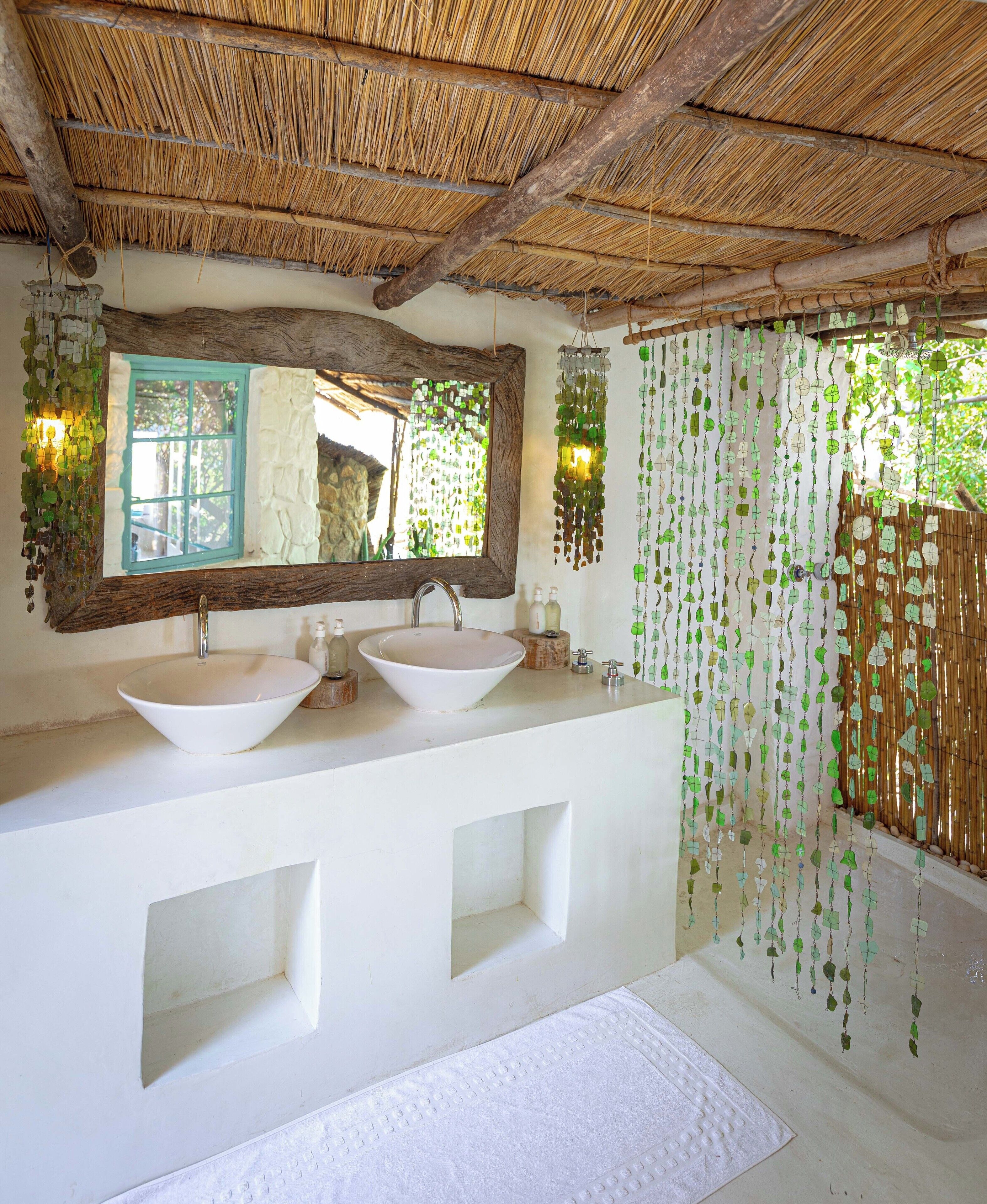 A bathroom with a large mirror, two sinks, and a hanging leaf decoration.