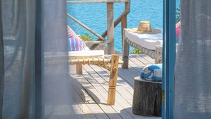 A wooden deck with a view of the sea, a lounge chair, and a table with a hat. - Kaya Mawa (Likoma Island)