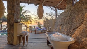 A wooden deck with a hot tub, lounge chairs, and a view of the sunset over the sea. - Kaya Mawa (Likoma Island)