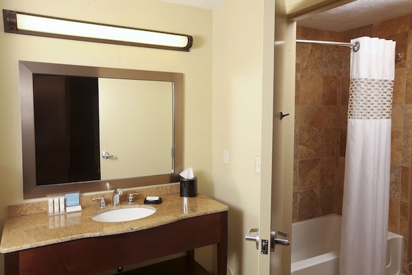 A bathroom with a sink, mirror, and shower area.
