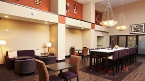 A hotel lobby with a seating area, a long dining table, and a reception desk.