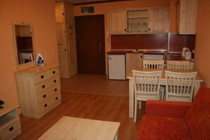 Une cuisine compacte avec des meubles en bois, un petit réfrigérateur et un coin repas comprenant une table et des chaises.