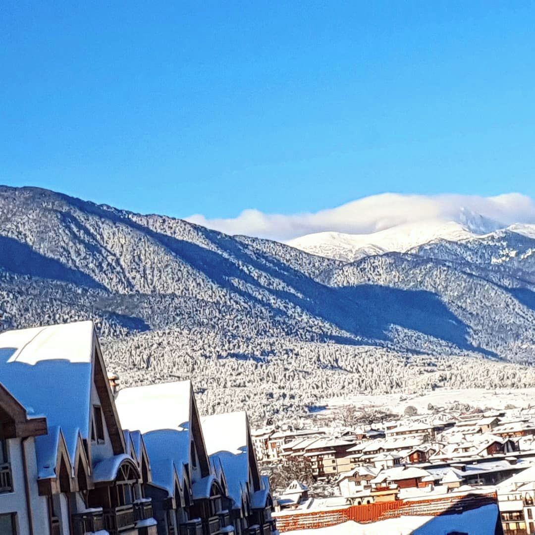 A town with snow-covered buildings and mountains in the background.