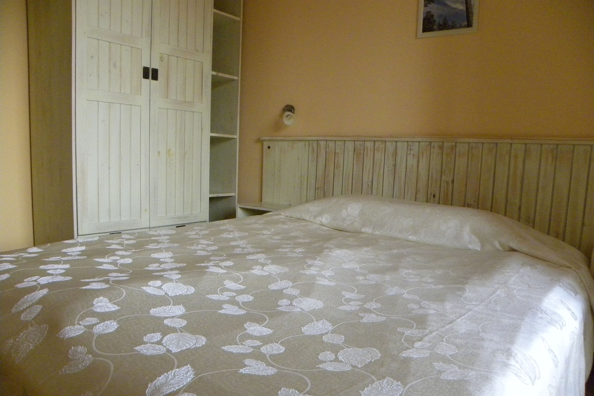 A bedroom with a bed, a wardrobe, and a wall-mounted light fixture.