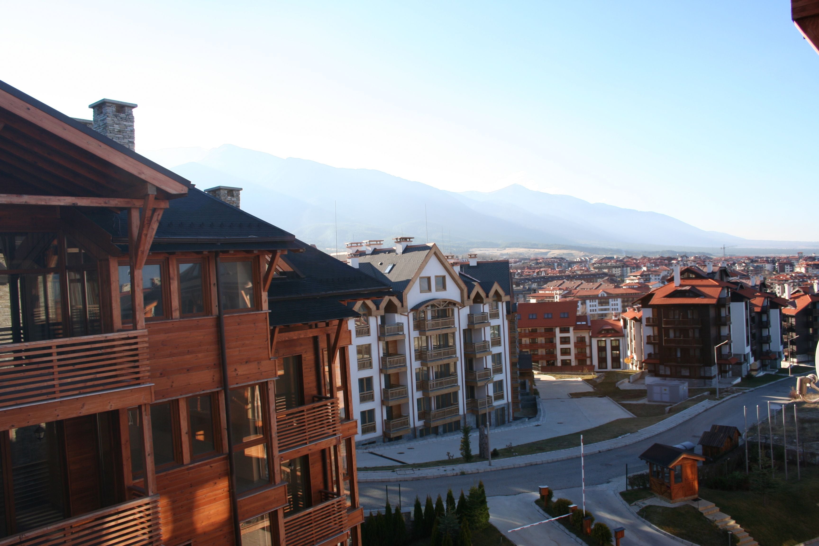 Un hôtel à étages, doté de balcons et offrant une vue sur les montagnes en arrière-plan.