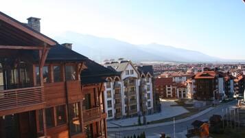 Un hôtel à étages, doté de balcons et offrant une vue sur les montagnes en arrière-plan.